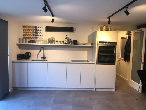 una cocina con armarios blancos y fregadero en Brand new studio outhouse Putney SW15, en Londres