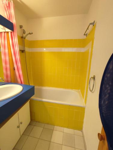 La salle de bains jaune est pourvue d'une baignoire et d'un lavabo. dans l'établissement AQUAPLAGE Joli appartement RDC piscine 1 ère ligne mer Richelieu Cap d'Agde, au Cap d'Agde