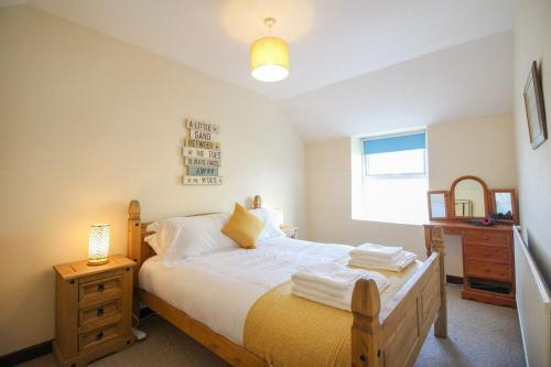 a bedroom with a bed and a dresser and a window at Sunny Corner Cottage in Hayle