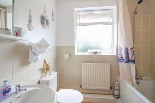 a bathroom with a sink and a toilet and a window at Sunny Corner Cottage in Hayle
