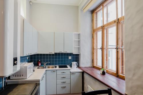 d'une cuisine avec des placards blancs, un évier et une fenêtre. dans l'établissement Dream Stay - Old Town City Wall Studio Apartment, à Tallinn