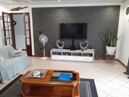 a living room with a tv and a coffee table at Charmante maison au cœur des 3 montagnes in Salazie