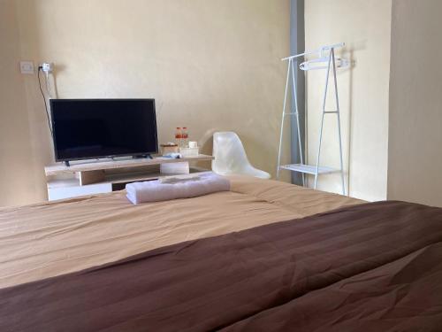 Schlafzimmer mit einem großen Bett und einem Flachbild-TV in der Unterkunft Tingang84 Guesthouse in Palangkaraya