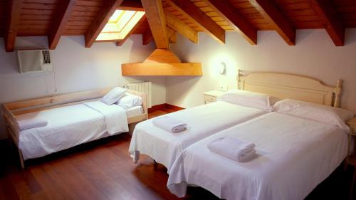 a bedroom with two beds with white sheets and a window at Hotel Palacio Branka in Mundaka