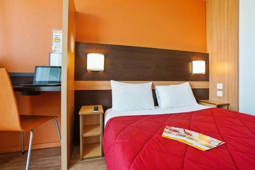 a bedroom with a bed and a desk with a computer at Première Classe Villejust in Villejust