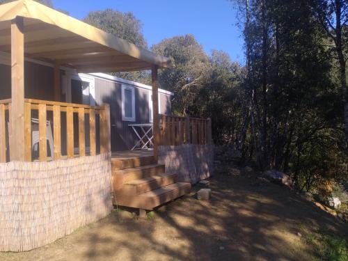 une maison avec une terrasse couverte, un portail et une clôture dans l'établissement Camping Les Eaux Vives, à Vero