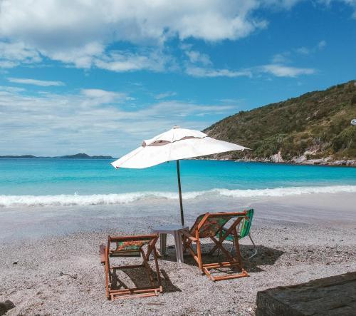 two chairs and an umbrella on a beach at Orlanova Hotel in Arraial do Cabo
