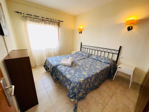 1 dormitorio con 1 cama con manta azul y ventana en Pier View Los Cristianos Free WiFi, en Los Cristianos