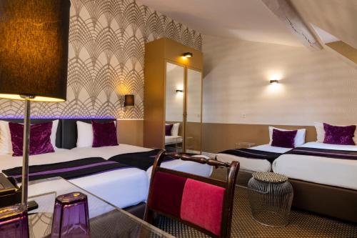 a hotel room with two beds and a table at ATN Hôtel in Paris