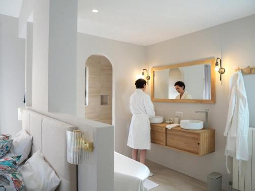 Una mujer parada en un baño mirándose en el espejo en Maison d'Hôtes L'Espigoulié en Sainte-Maxime