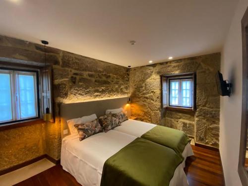 - une chambre avec un grand lit dans un mur en pierre dans l'établissement Casa Posto da Guarda Fiscal, à Melgaço