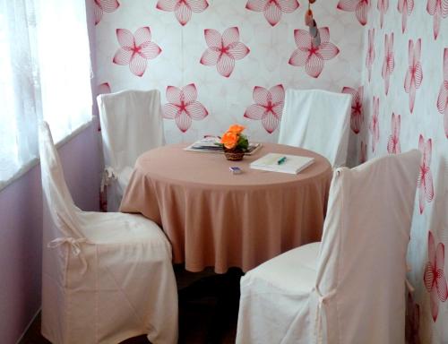 einen Tisch mit weißen Stühlen und eine rosafarbene Blumentapete in der Unterkunft Haus in Malchow in Malchow