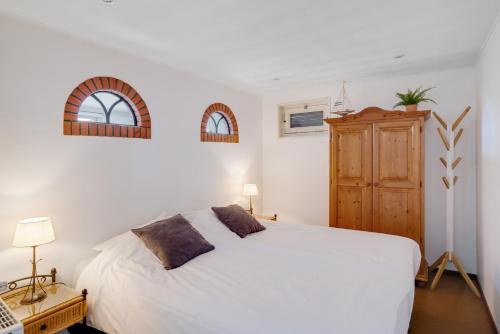 1 dormitorio con cama blanca y armario de madera en 't Zwanennest, en Egmond aan den Hoef