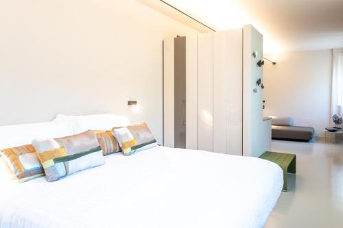 een witte slaapkamer met een wit bed met kussens bij Hotel Zurigo in Varazze