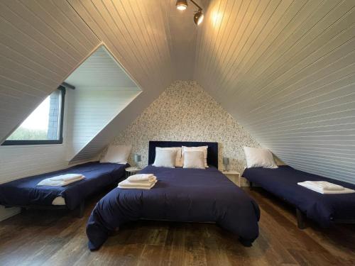 een slaapkamer met 2 bedden op een zolder bij Gîte de l'Archipel in Trélévern