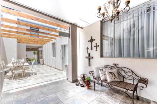 a porch with a bench and a cross on the wall at Adato Guesthouse in Potchefstroom