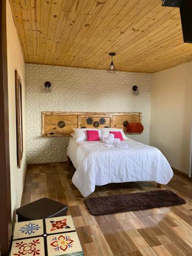 a bedroom with a bed with white sheets and pink pillows at Suíte Aconchego Mineiro in Ouro Preto