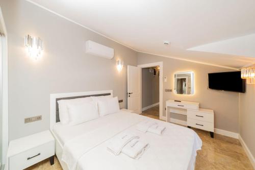 a bedroom with a white bed and a television at Nature Sea View Flat with Jacuzzi in Kas Antalya in Kas
