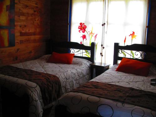 a bedroom with two beds with red pillows and a window at Hotel Campestre El Refugio de Balsora in Filandia