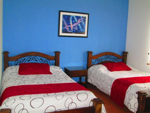 two beds in a room with blue walls at Hotel Campestre El Refugio de Balsora in Filandia