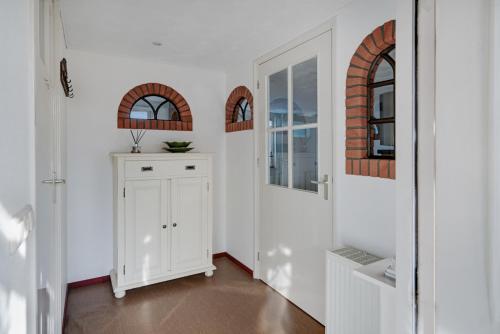 a hallway with white walls and a white cabinet at 't Zwanennest in Egmond aan den Hoef