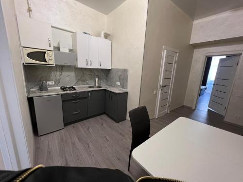 eine Küche mit weißen Schränken und einem Tisch im Zimmer in der Unterkunft Kulisha 2bedroom apartment near Opera House with balcony in Lwiw