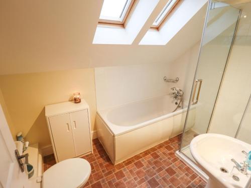 a bathroom with a toilet and a tub and a sink at Acer Cottage in Boston