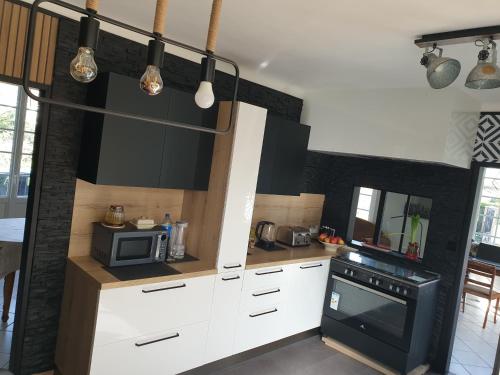 La cuisine est équipée de placards blancs et d'un four avec plaques de cuisson noires. dans l'établissement BIENVENUE chez VOUS, à Socx