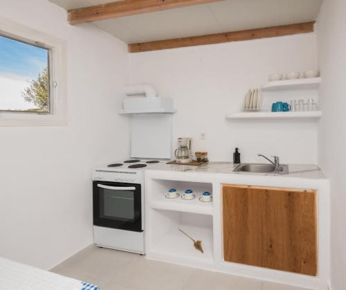 a white kitchen with a stove and a sink at Sarantis apartments in Provatas