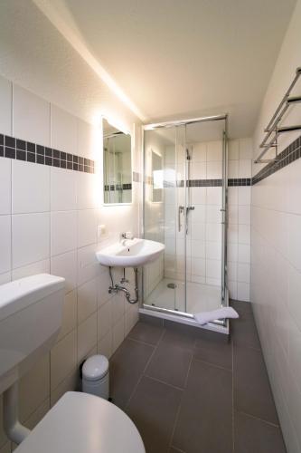 a bathroom with a sink and a shower and a toilet at Aparthotel Stralsund Studios und Apartments in Stralsund