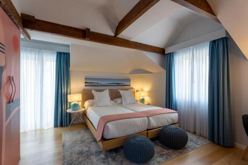 a bedroom with a large bed with blue curtains at Hotel Sol Boutique in Santander