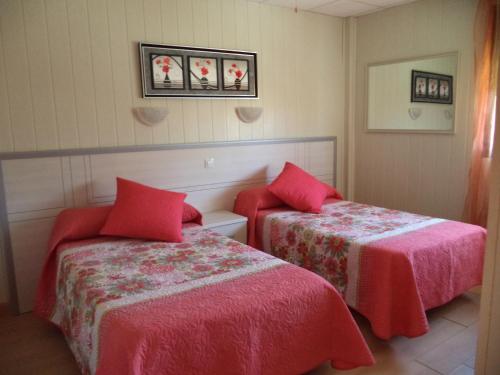 two beds in a hotel room with red sheets at Hotel A Santiago in Belorado