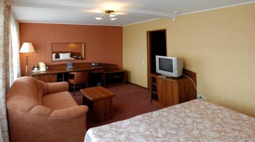 Habitación de hotel con cama, escritorio y TV. en Lovech Hotel, en Riazán