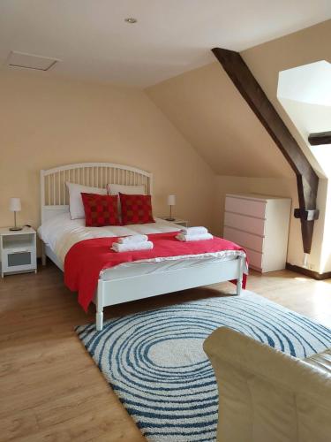- une chambre avec un lit doté d'oreillers rouges et d'un tapis dans l'établissement La Grande Maison - Les Gîtes de la Lohuas, à Les Champs-Géraux