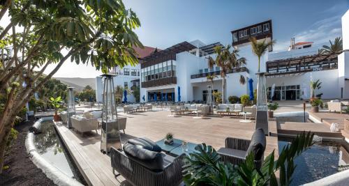 un complejo con piscina, sillas y palmeras en Fuerteventura Princess, en Playa de Jandía