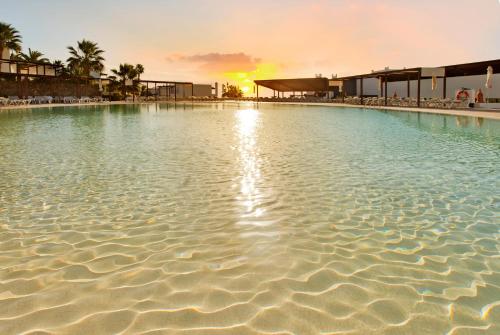 a large pool of water with a sunset in the background at Esencia de Fuerteventura by Princess in Playa Jandia