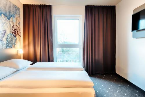 duas camas num quarto de hotel com uma janela em B&B Hotel Emden em Emden