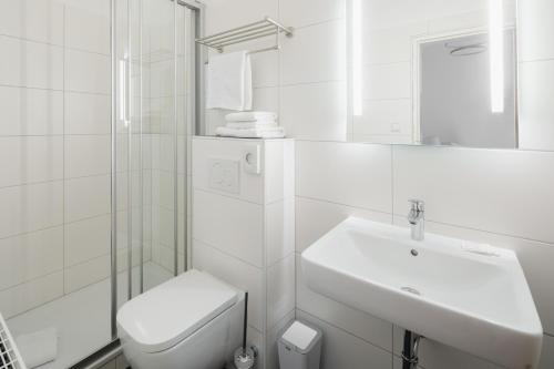 a white bathroom with a toilet and a sink at Hotel am Denkmal Norderney in Norderney