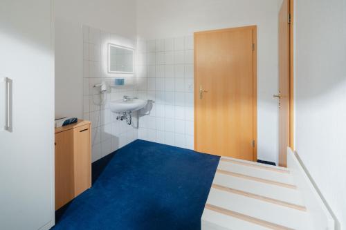 ein Bad mit einer Treppe, die zu einem Waschbecken und einer Tür führt in der Unterkunft Hotel am Denkmal Norderney in Norderney