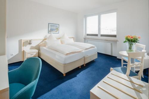 a bedroom with a bed and a desk and a chair at Hotel am Denkmal Norderney in Norderney