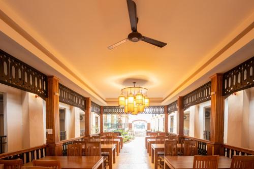 a restaurant with wooden tables and a ceiling fan at Peacock De Pai Hotel in Pai