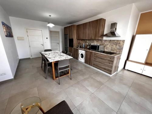 una cucina con tavolo e piano di lavoro di Mediterranea 2 Bedroom Smart Apartment a San Pawl il-Baħar
