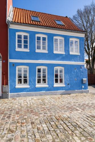 a blue house with white windows on a cobblestone street at City Harbour House in Sønderborg
