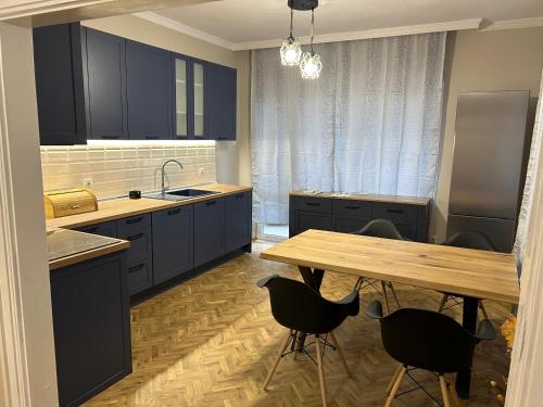 cocina con armarios azules y mesa de madera en Niya Apartment Bourgas, en Burgas