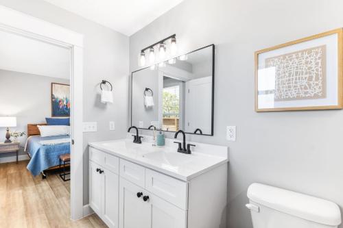 Baño blanco con lavabo y espejo en Brand New Bungalow with King Bed Suites in St Aug en Saint Augustine