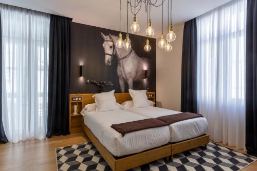 a bedroom with a bed with a painting of a horse on the wall at Hotel Sol Boutique in Santander