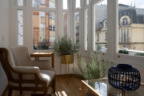 Habitación con ventanas, silla y mesa. en Hotel Sol Boutique en Santander