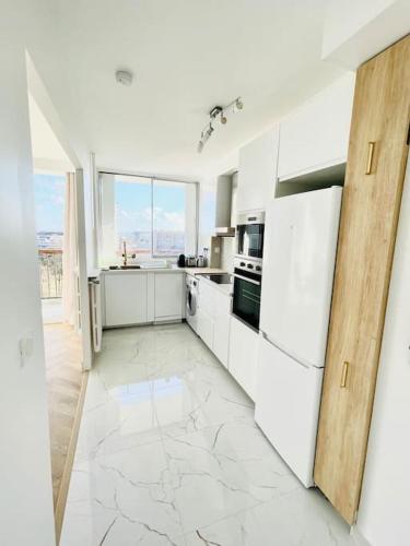 une cuisine avec des appareils blancs et une grande fenêtre dans l'établissement Superbe 50m² calme et élégant, proche Paris, à Villejuif