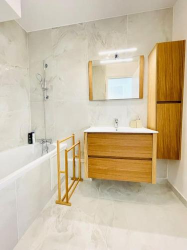 a bathroom with a sink and a mirror and a tub at Superbe 50m² calme et élégant, proche Paris in Villejuif