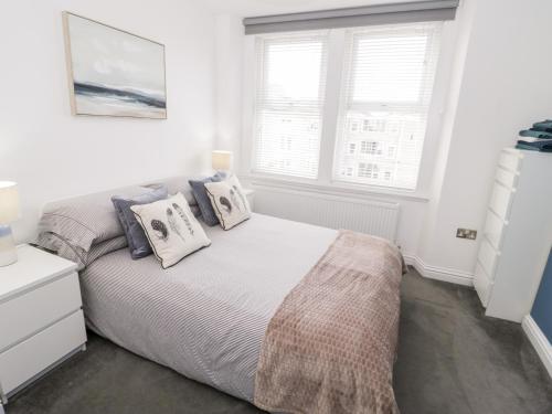 a white bedroom with a bed and two windows at Apartment 6 in Llandudno